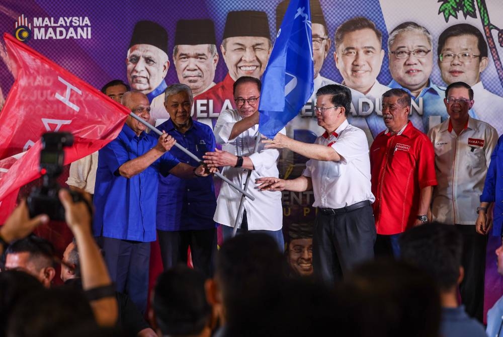 Anwar menyampaikan bendera parti kepada Kon Yeow (tiga dari kanan) dan Pengerusi Badan Perhubungan UMNO Negeri Datuk Musa Sheikh Fadhir (kiri) pada Jelajah Perpaduan Madani dan Pelancaran Jentera Perpaduan Pulau Pinang malam ini. - Foto Bernama