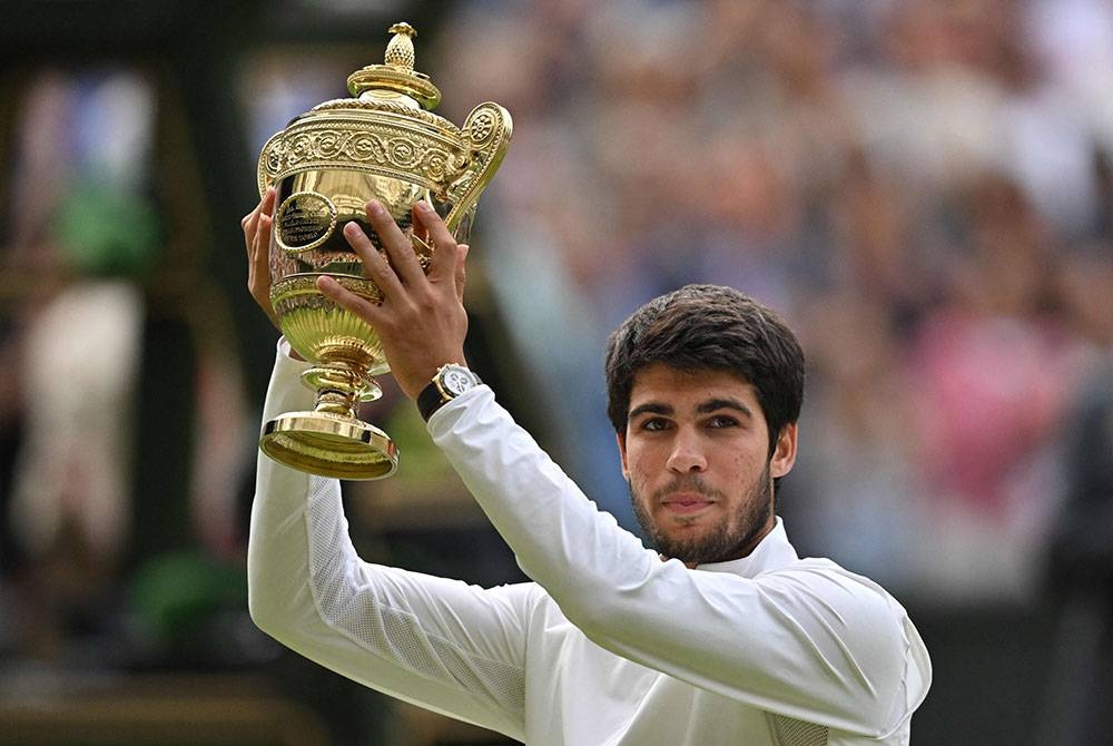 Alcaraz menjulang trofinya selepas menewaskan Djokovic pada perlawanan akhir perseorangan lelaki Kejohanan Tenis Wimbledon 2023. - Foto AFP