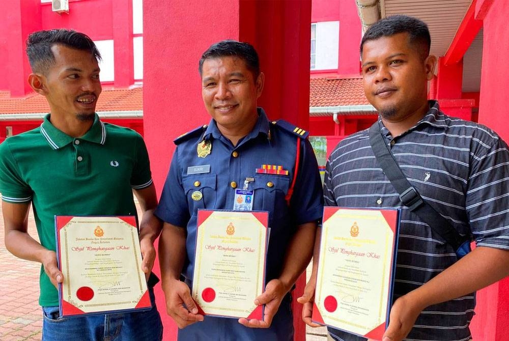 Tuan Mohamad Sukri (tengah) bersama Muhammad Amir Firdaus (kiri) dan Mohamad Suhazaki Hakim (kanan) menerima sijil penghargaan daripada JBPM Kelantan.