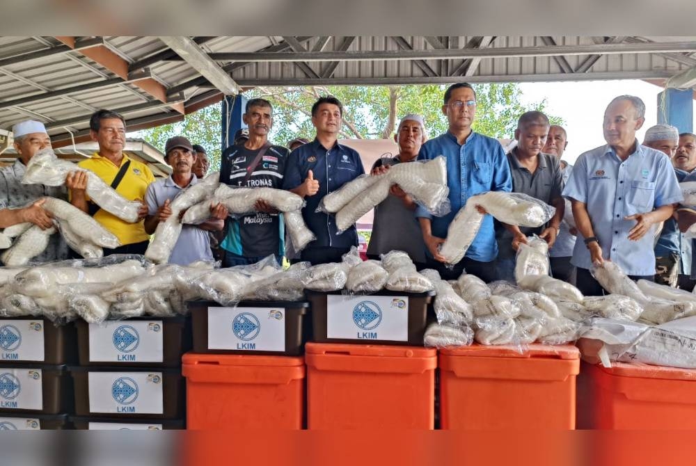 Muhammad Faiz (tengah) bersama nelayan yang menerima bantuan peralatan pada Program Rahmah Mesra Madani bersama nelayan di Kuala Kedah pada Isnin.