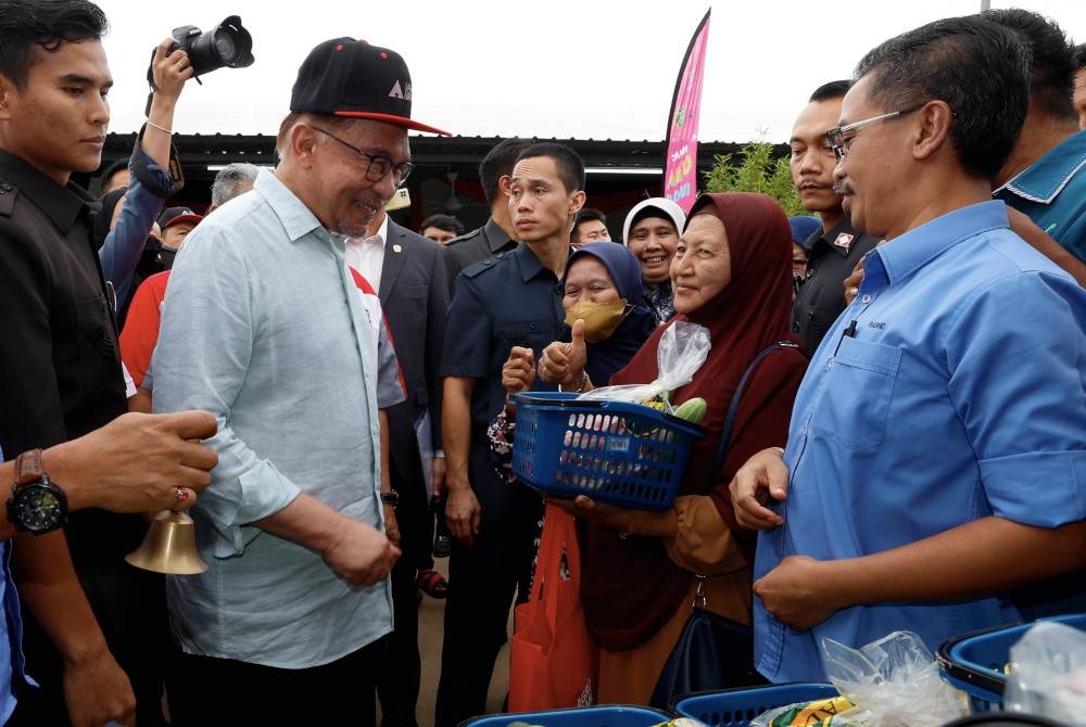 Anwar (kiri) beramah mesra bersama pengunjung ketika melawat tapak gerai jualan Agro Madani pada Majlis Program Sentuhan Agro Madani Peringkat Negeri Selangor di Sekinchan hari ini. - Foto Bernama