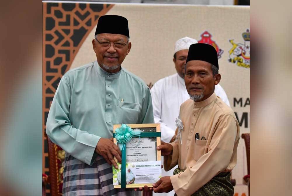 Ahmad (kiri) menyampaikan Anugerah Tokoh Hijratul Rasul 1445H peringkat negeri Kelantan kepada Prof Emeritus Dr Ab Aziz (kanan).