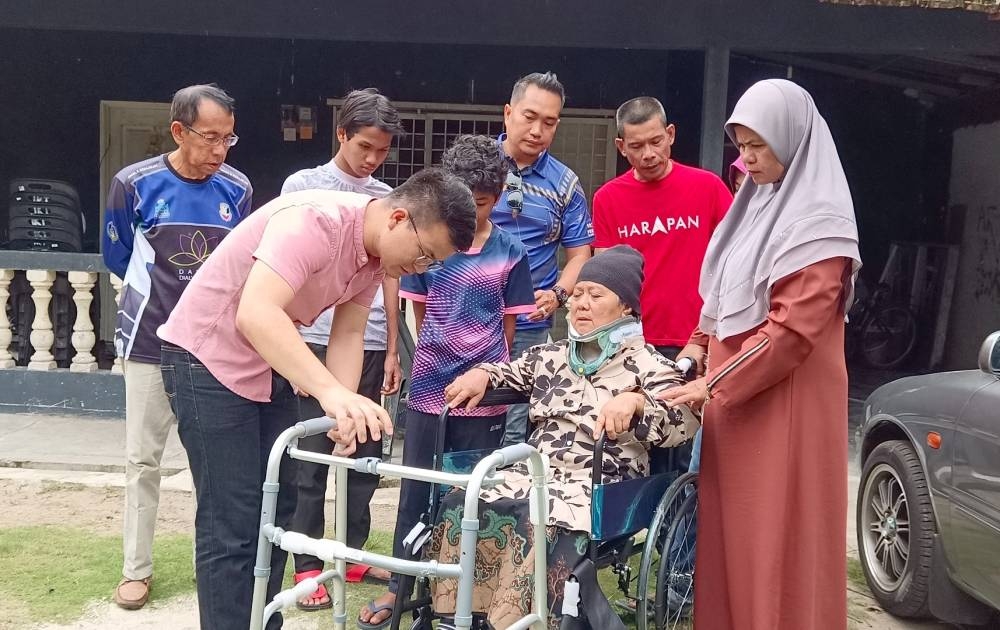 Steven Tiw (kiri) menyerahkan &#039;walking frame&#039; kepada Noraini bagi membantu proses pemulihan selepas terbabit dalam kemalangan yang turut mengorbankan anak dan menantunya, minggu lalu.