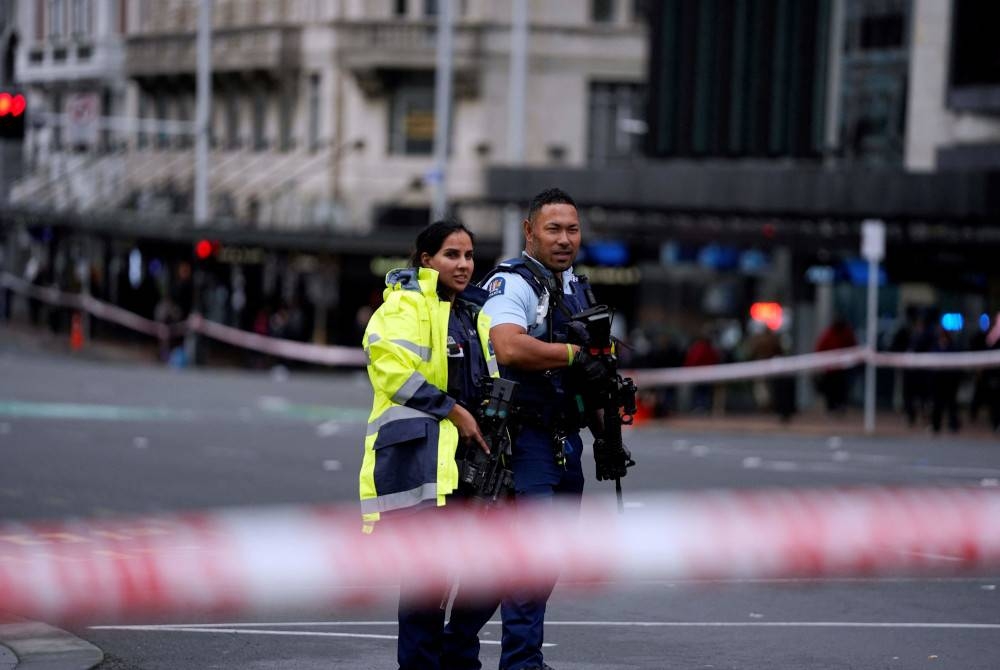 Pegawai polis berdiri di tempat kejadian tembakan di pusat bandar Auckland pada Khamis. - Foto AFP