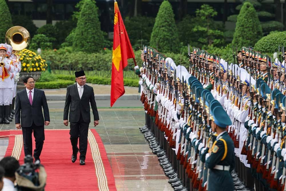 Anwar diiringi rakan sejawatnya Minh Chinh memeriksa kawalan kehormat pada sambutan rasmi sempena lawatan dua hari ke Vietnam di Istana Presiden pada Khamis.   - Foto: Bernama