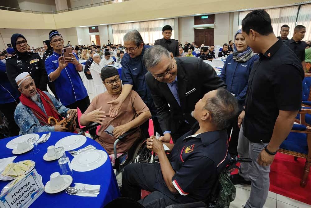 Shamsul (berdiri dua dari kanan) beramah mesra dengan penerima bantuan zakat.