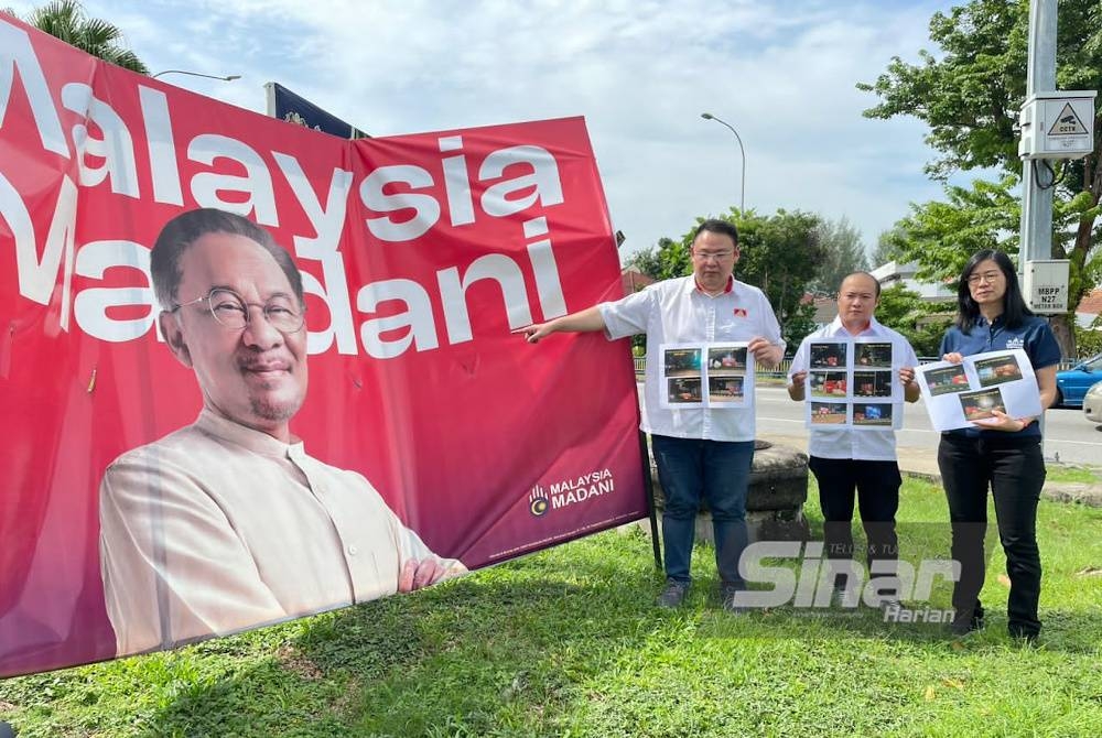 Andrew (kiri) menunjukkan salah satu papan iklan &#039;Malaysia Madani&#039; yang sudah senget di kawasan Bukit Jambul.