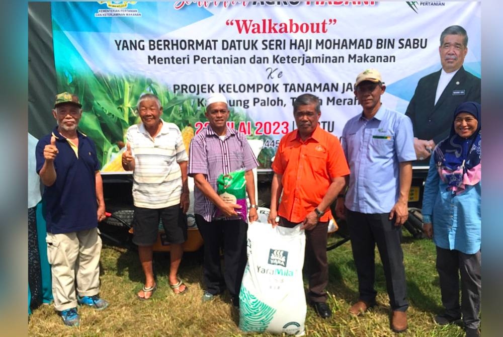 Mohamad (tiga dari kiri) menyampaikan bantuan baja kepada penanam jagung di Tanah Merah.