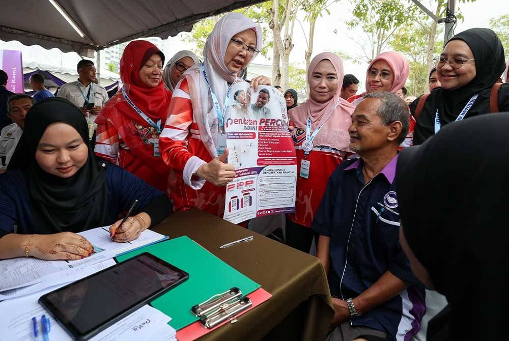 Dr Zaliha (tiga, kiri) menerangkan mengenai program Perubatan Percuma Madani kepada penduduk di PPR Padang Hiliran pada Ahad. - Foto Bernama