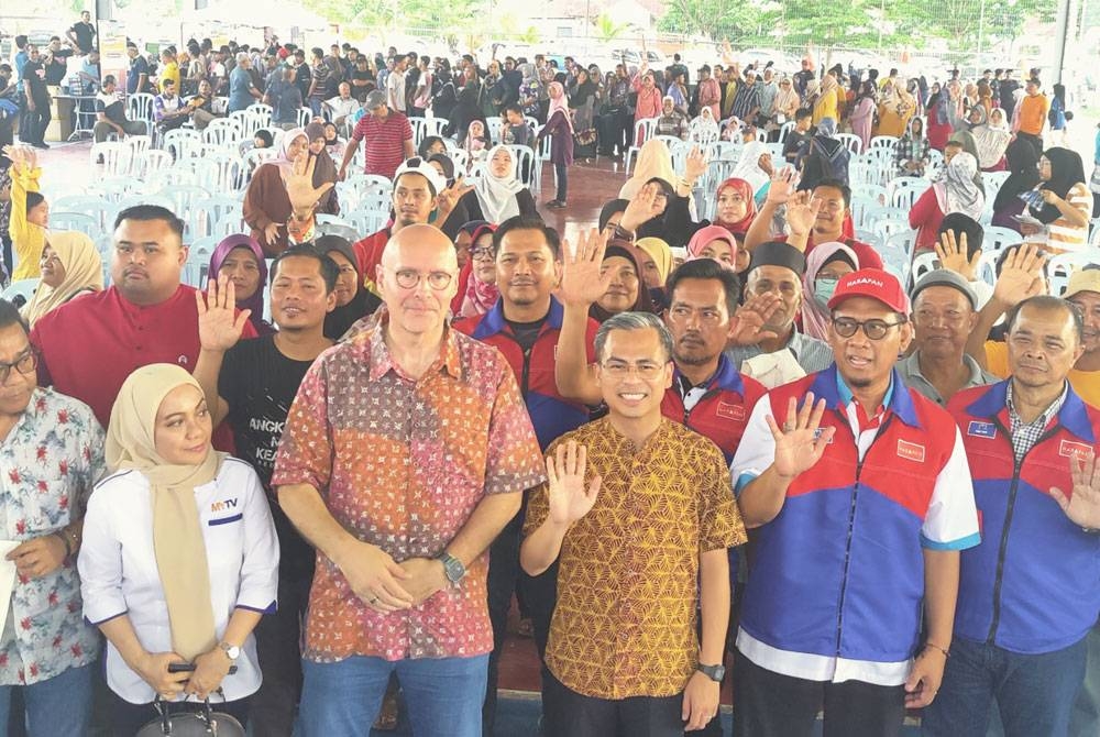 Fahmi (tiga dari kanan) bergambar bersama teamu jemputan dan rakyat yang hadir pada Jelajah Madani 2.0 DUN Permatang di Dewan Terbuka Taman Desa Mawar, Tanjong Karang pada Ahad.