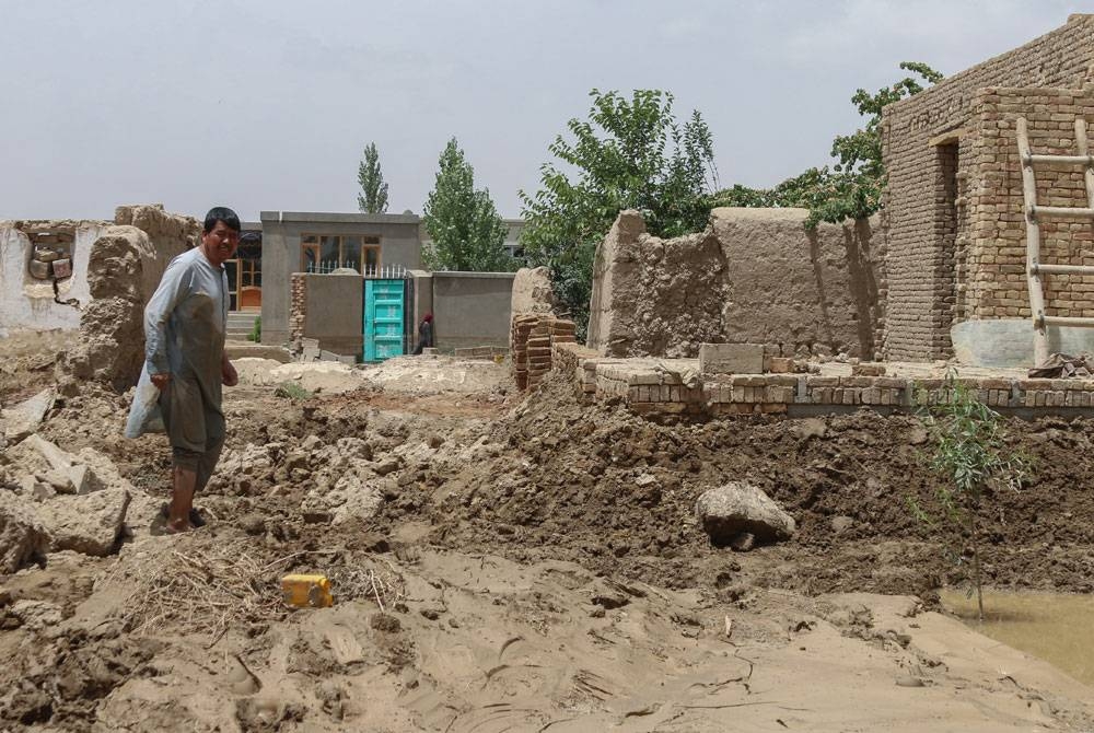 Seorang lelaki Afghanistan meninjau di jalan yang diselaputi lumpur akibat banjir kilat di kawasan Khair Abad, wilayah Ghazni. - Foto: AFP