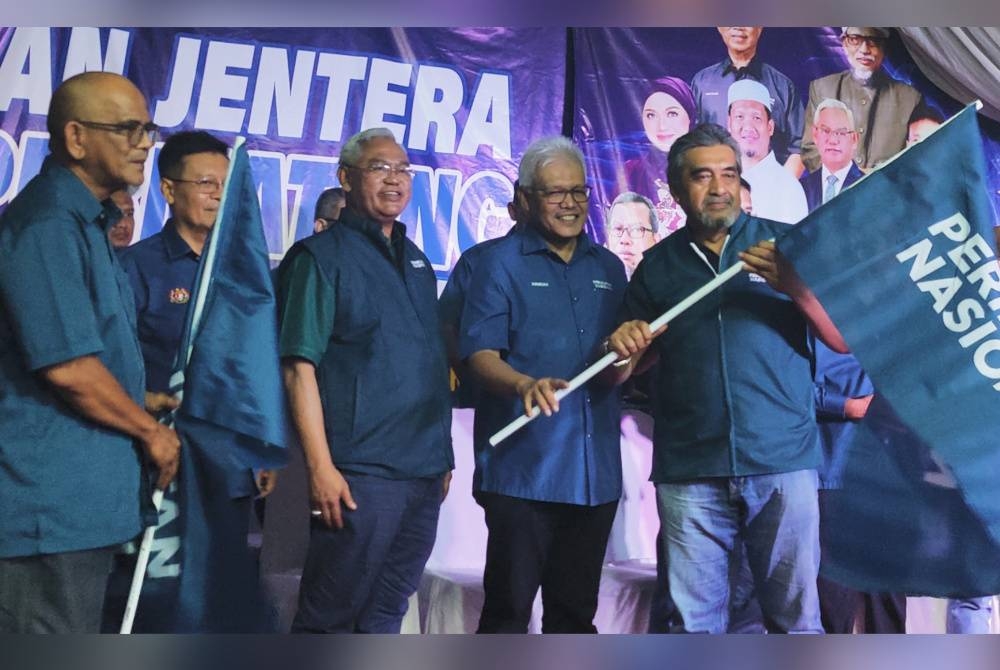 Hamzah (dua kanan) menyerahkan bendera PN kepada salah seorang jentera parti selepas Majlis Pelancaran Jentera PN DUN Permatang di Tanjong Karang pada malam Ahad.