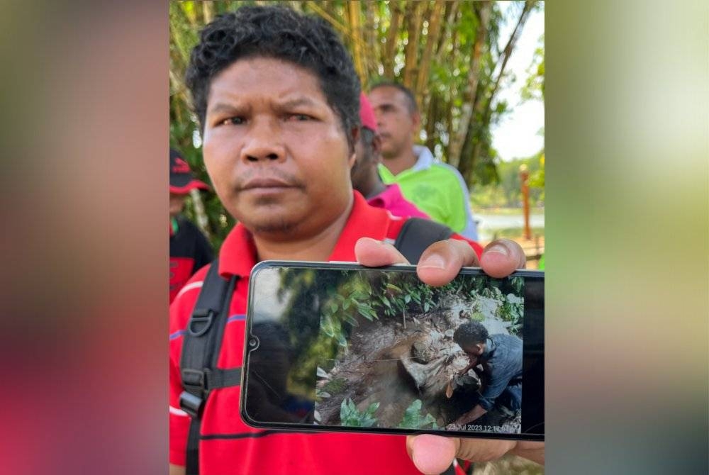 Ramli menunjukkan gambar kawasan tadahan air tandak yang dipercayai terkesan ekoran aktiviti penerokaan tanah bagi tujuan perladangan. - Foto Bernama