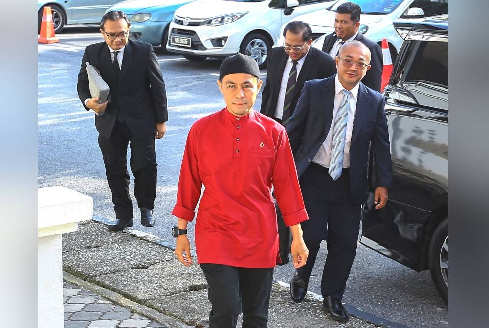 Azman berbaju merah hadir bersama peguamnya ketika hadir ke mahkamah