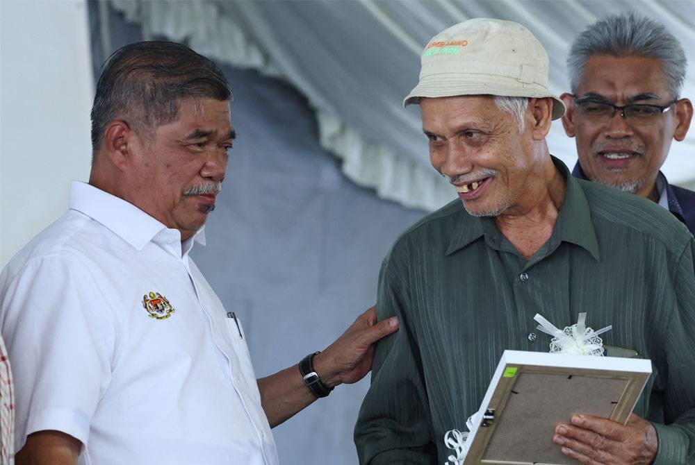 Mohamad Sabu (kiri) menyampaikan sumbangan kepada petani pada Program Sentuhan Agro Madani dan Penyampaian Bantuan Ihsan dan Bantuan Khas kepada pesawah MADA di Pertubuhan Peladang Kawasan Tajar pada Rabu. Foto: Bernama