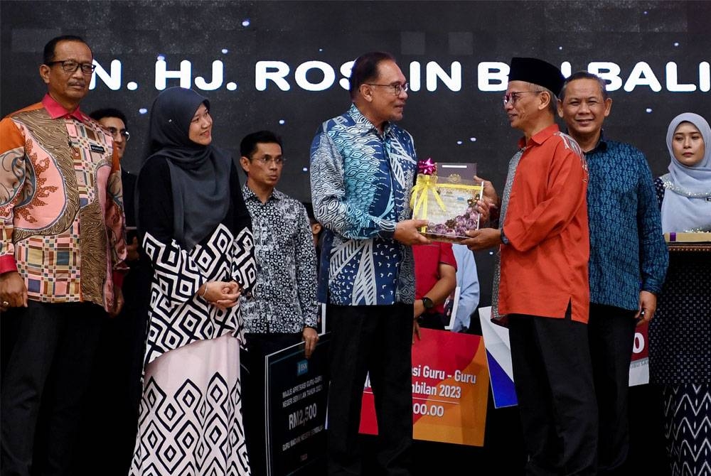 Anwar (empat dari kiri) menyampaikan Anugerah Utama Guru Madani Negeri Sembilan kepada Bekas Pengetua Sekolah Menengah Kebangsaan (SMK) King George V, Roslin Balia (tiga dari kanan) pada Majlis Apresiasi Guru-Guru Peringkat Negeri Sembilan di Dewan Majlis Bandaraya Seremban pada Khamis. - FOTO: BERNAMA