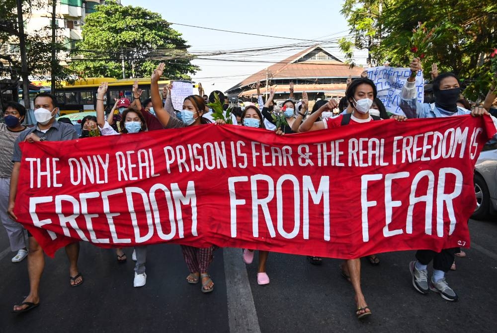 Penunjuk perasaan memegang sepanduk yang menentang rampasan kuasa tentera di Yangon. - AFP