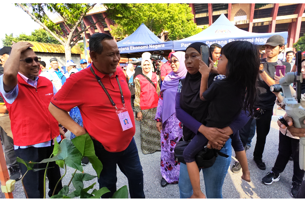 Aminuddin (tengah) beramah mesra dengan seorang pengunjung di Pasar Tani Paroi Jaya.