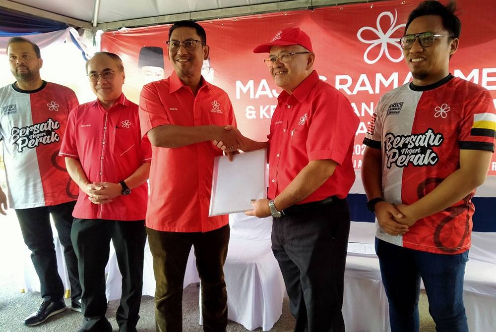 Ahmad Faizal (tengah) menerima borang keahlian baharu daripada Pengerusi Sayap Bersekutu Bersatu Perak, Dr Richard Ng ketika Majlis Ramah Mesra dan Kemasukan Keahlian Baharu Bersatu Perak di pekarangan Pejabat Bersatu Perak pada Ahad.