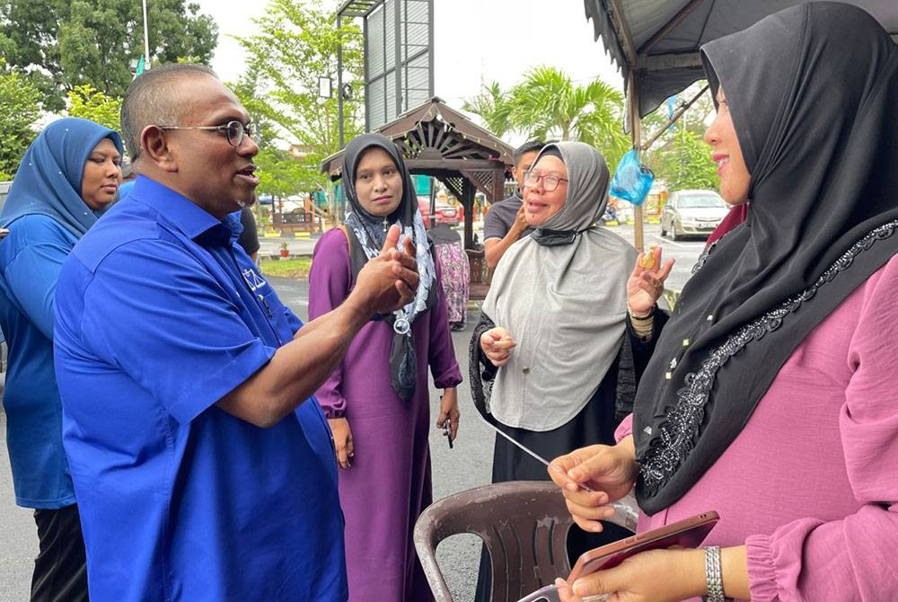 Shaik Hussein (kiri) menyantuni masyarakat di Masjid Merbau Kudong ketika siri kempennya untuk pilihan raya negeri pada Isnin.