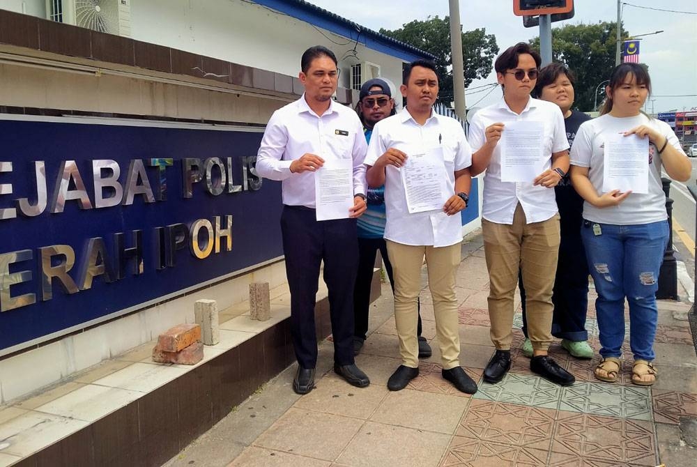 Mohamad Norriduan (dua dari kiri) menunjukkan salinan laporan polis yang dibuat di Ibu Pejabat Polis Daerah (IPD) Ipoh di sini pada Isnin.