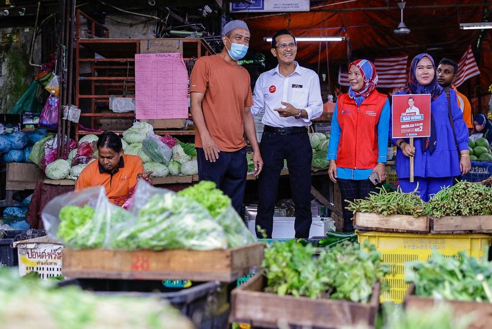 Bau Wong menyantuni penduduk setempat ketika berkempen di Pasar Besar Sungai Petani pada Isnin. - Foto Bernama