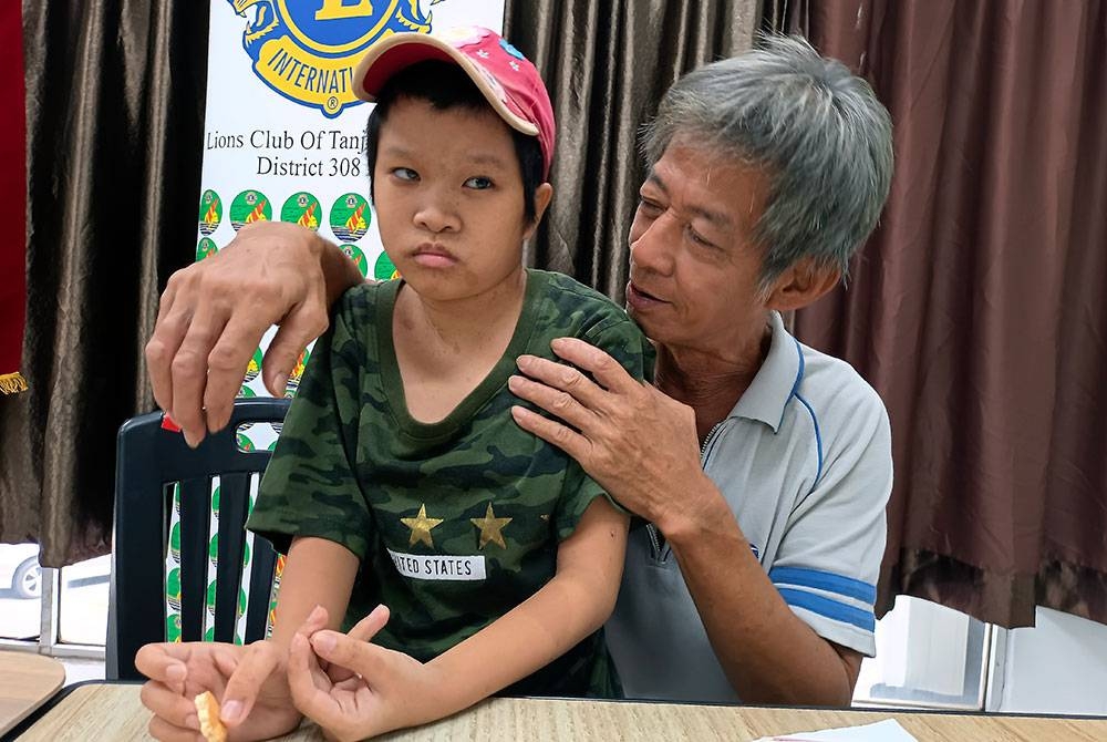 Hock Teng (kanan) bersama Jun Yee yang juga remaja OKU menderita penyakit tulang belakang bengkok ketika ditemui di Melaka Raya, Melaka hari ini.