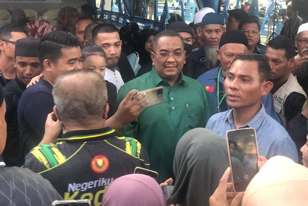 Sanusi (tengah) memenuhi permintaan orang ramai untuk bergambar ketika hadir majlis Sembang Santai bersama MB Kedah di Flat Alor Malai, pada Rabu.