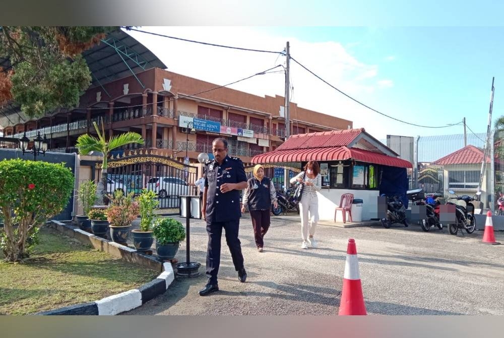 Tertuduh (kanan) diiringi pegawai polis sebaik tiba di pekarangan mahkamah di Tampin pada Jumaat.