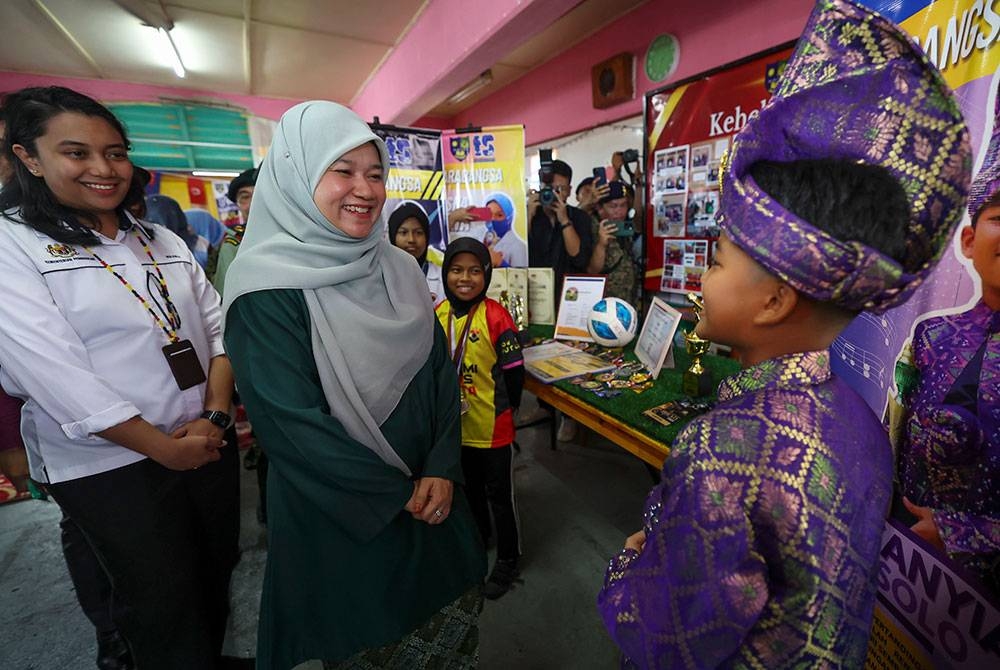 Fadhlina (dua dari kiri) beramah mesra dengan pelajar pada program pelancaran Gotong-royong Madani peringkat negeri dan sambutan Jubli Intan Hari Ulang Tahun Briged Pertama Infantri Malaysia pada Jumaat.