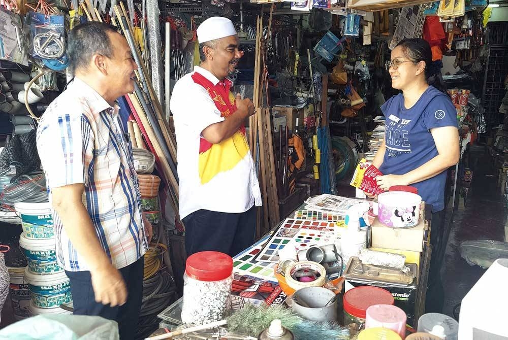 Mohamad Khir (tengah) beramah-mesra bersama peniaga di Pekan Tanjong Karang pada Sabtu.