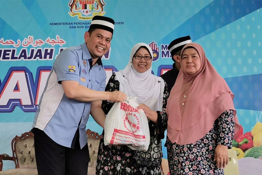 Fuziah (tengah) bersama Pengarah KPDN Terengganu, Saharuddin Mohd Kia (kiri) menyampaikan sumbangan barangan dapur kepada penerima sempena program Jelajah Jualan Rahmah di Tapak Pasar Malam Tok Adis di Kuala Terengganu pada Sabtu.