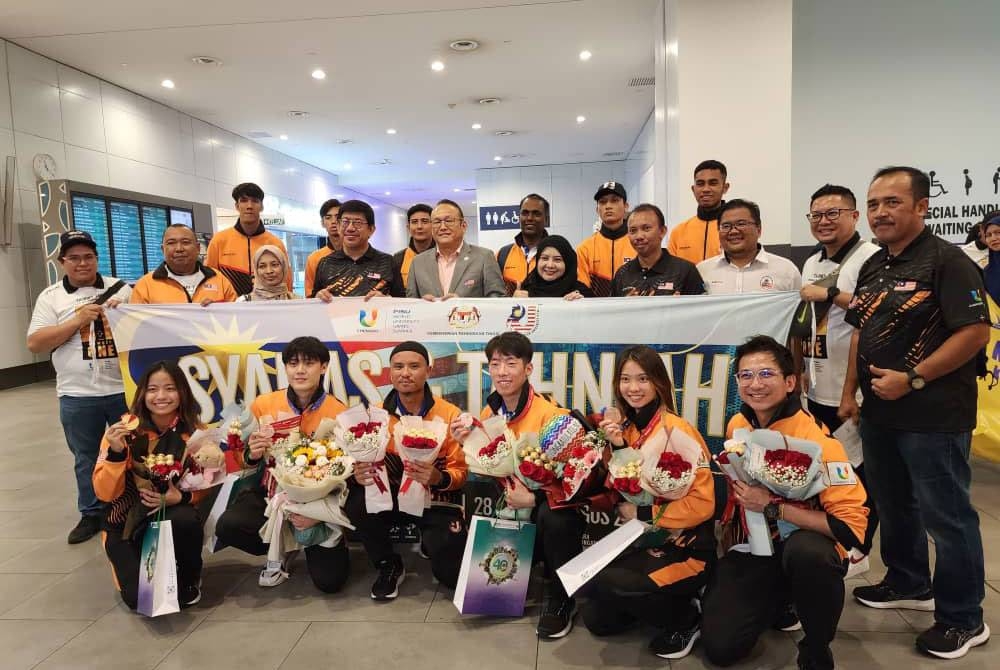 Atlet wushu Universiade Chengdu negara bergambar bersama Megat Sany dan Kim Fatt selepas skuad negara tiba di KLIA pada Sabtu.