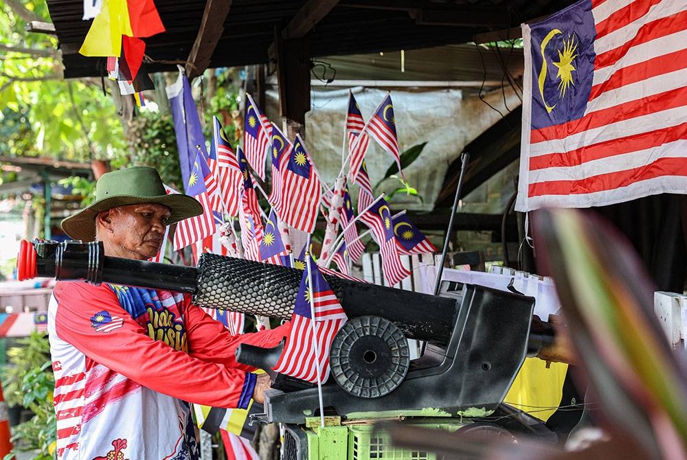 Warga Perak, Tazar Alang Ibrahim, 63, menghiasi replika meriam katak dengan Jalur Gemilang menjelang sambutan Hari Kebangsaan ke-66 pada 31 Ogos ini yang bertemakan Tekad Perpaduan Penuhi Harapan di Jalan Tasek pada Sabtu. - Foto Bernama