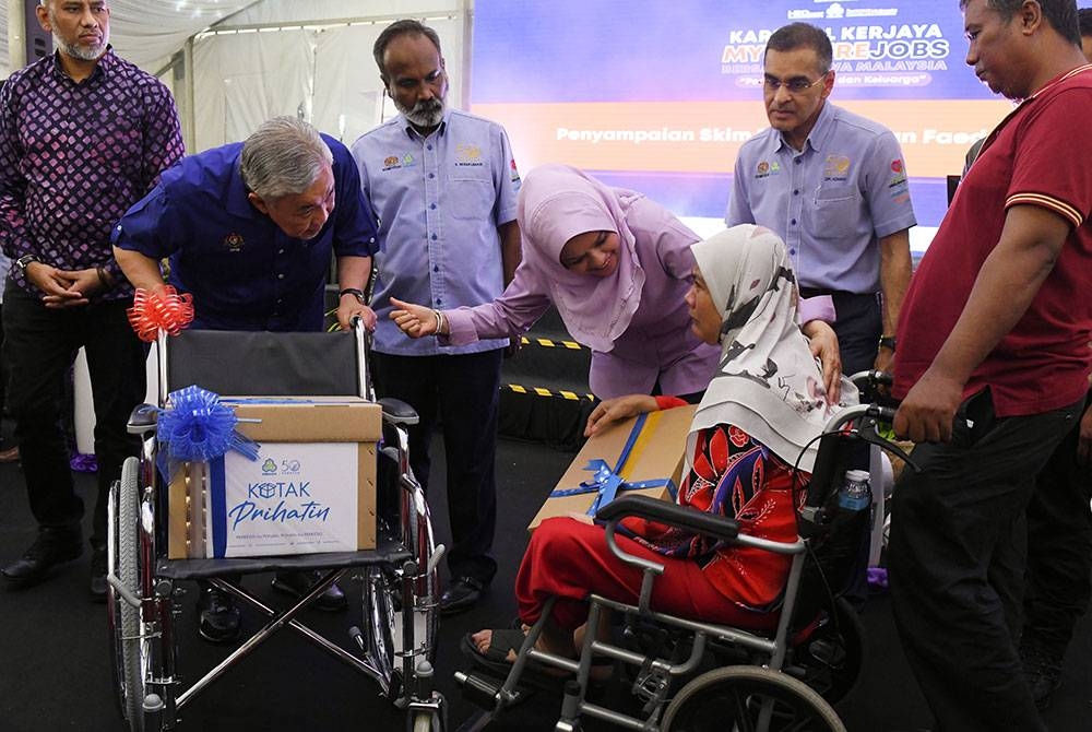 Ahmad Zahid (kiri) beramah mesra dengan Siti Rokiah Baharom, 52, (dua dari kanan) sambil disaksikan Sivakumar (tiga dari kiri) dan Shahrizat (tiga dari kanan).semasa menyampaikan skim perlindungan faedah PERKESO di karnival kerjaya MyFuture Jobs Bersama Hawa Malaysia, pada Sabtu. - Foto Bernama