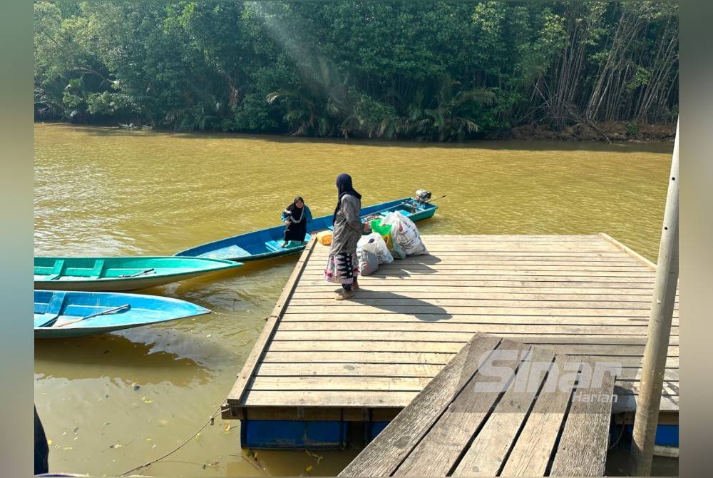 Penduduk memunggah barangan keperluan ke dalam bot untuk dibawa ke rumah di pulau di Tumpat.