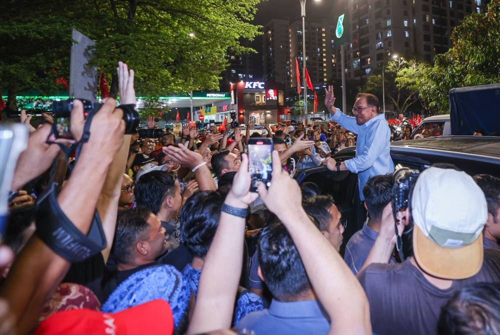 Anwar melambaikan tangan kepada penyokong ketika hadir pada Ceramah Jelajah Perpaduan Madani di Petaling Jaya malam Ahad. - Foto Bernama