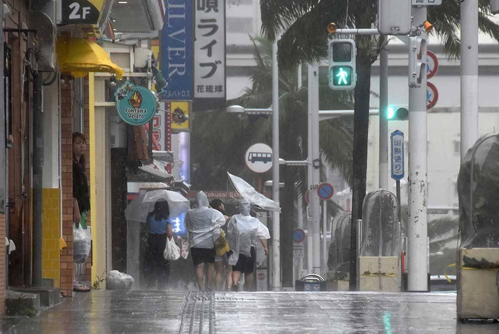 Orang ramai berjalan di sepanjang Kokusai-dori di bawah angin kencang dan hujan oleh Taufan Khanun di Naha, Wilayah Okinawa, Jepun, 2 Ogos lalu. - Foto EPA