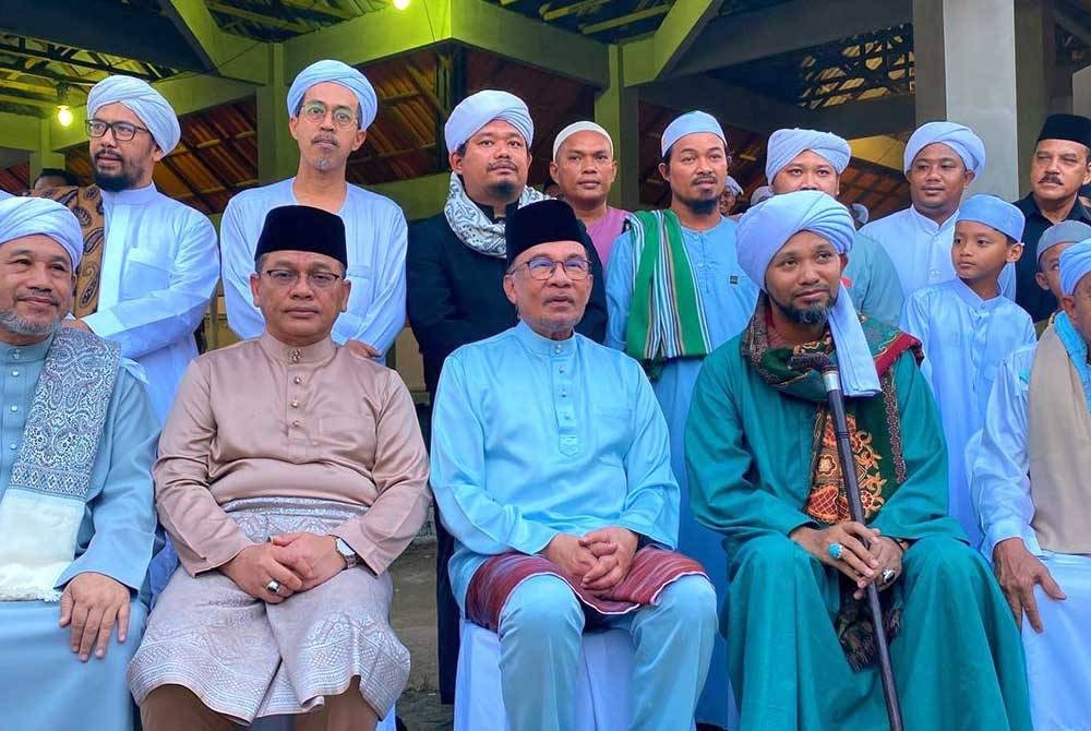 Anwar (tengah) bersama Ustaz Muhaizad (dua,kanan) bergambar bersama warga Madrasah Ribat Al-Musthofa, di Kampung Bagan Bawah, Pulai Condong, Machang pada Isnin.