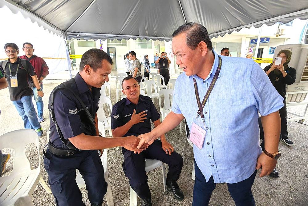 Aminuddin bersalam dengan angota polis yang menunggu giliran untuk mengundi awal di Balai Polis Sikamat