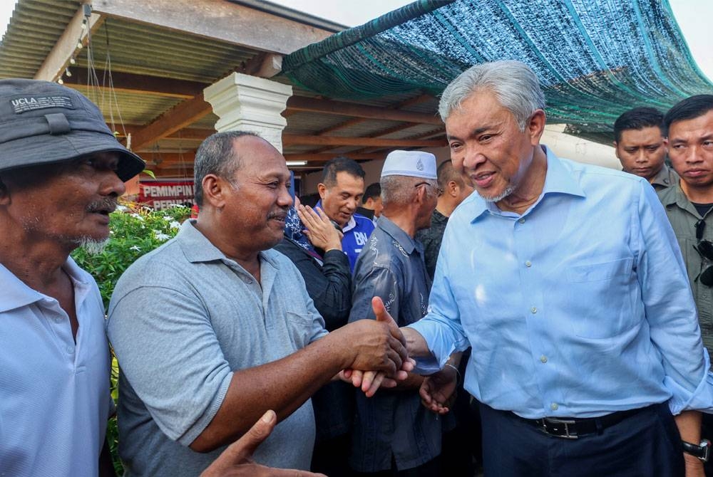 Ahmad Zahid (kanan) bersalaman bersama penduduk setempat sempena Program Pemimpin Bersama Masyarakat di Perumahan Nelayan Tok Bali pada Rabu. - Foto: Bernama