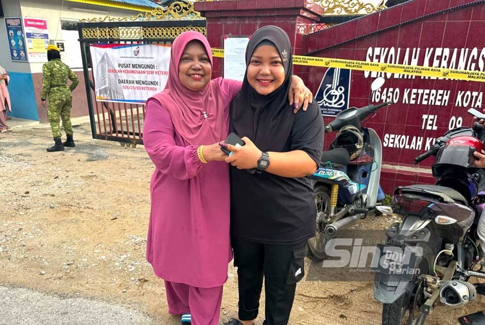 Sarifah (kiri) yang dipapah Ummu Amirah (kanan) keluar dari pusat mengundi di SK Seri Ketereh di Kota Bharu.