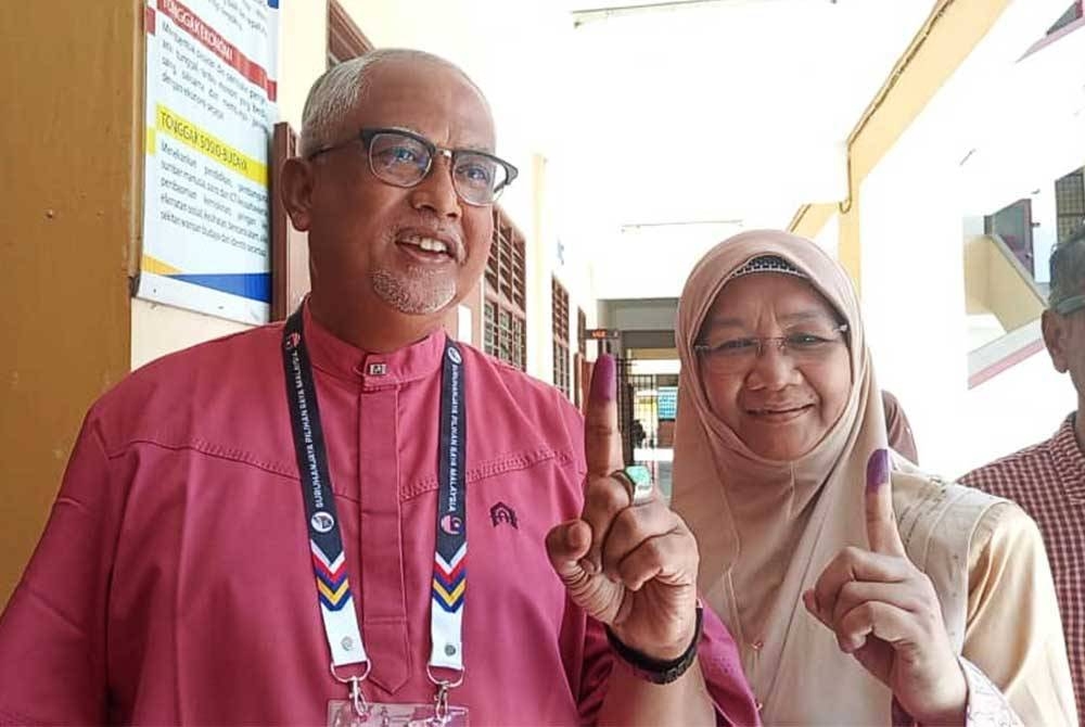 Calon Pakatan Harapan (PH) Dewan Undangan Negeri (DUN) Alor Mengkudu, Datuk Mahfuz Omar (kiri) dan isteri, Datin Ruswati Jaafar menunjukkan jari mereka yang berdakwat selepas mengundi di Kolej Tingkatan Enam Sultan Sallehuddin di Hutan Kampung,di sini, pada Sabtu.