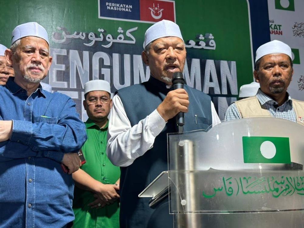 Ahmad (tengah) telah mengumumkemenangan PN di Dataran Medan Ilmu, Kota Bharu pada Sabtu.
