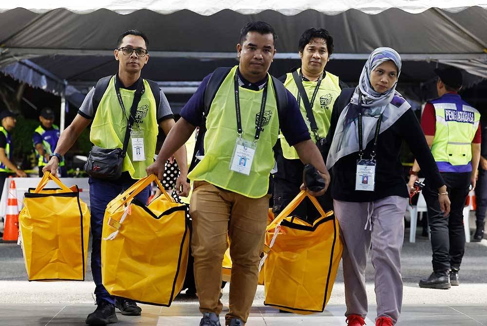 Petugas-petugas SPR menyusun peti undi di Pusat Penjumlahan Rasmi Undi DUN N40 Kota Anggerik di Dewan Besar Tanjung MBSA Seksyen 19 pada Sabtu. - Foto Bernama