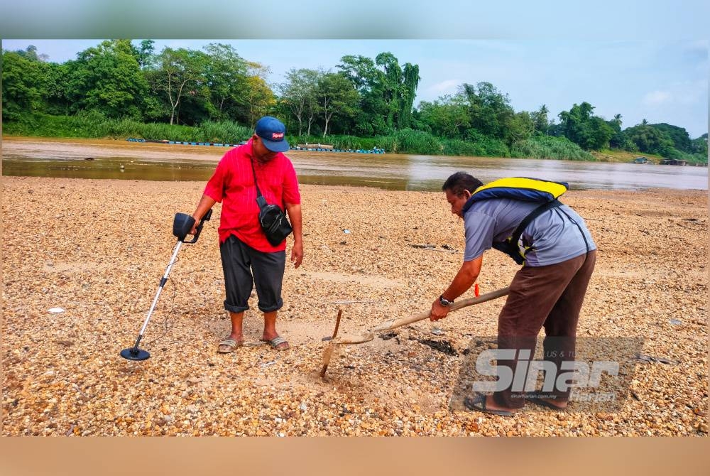 Hairulddin (kiri) dan Abdul Jamal mencari barangan berharga menggunakan pengesan logam di Sungai Pahang sebagai pendapatan sampingan.