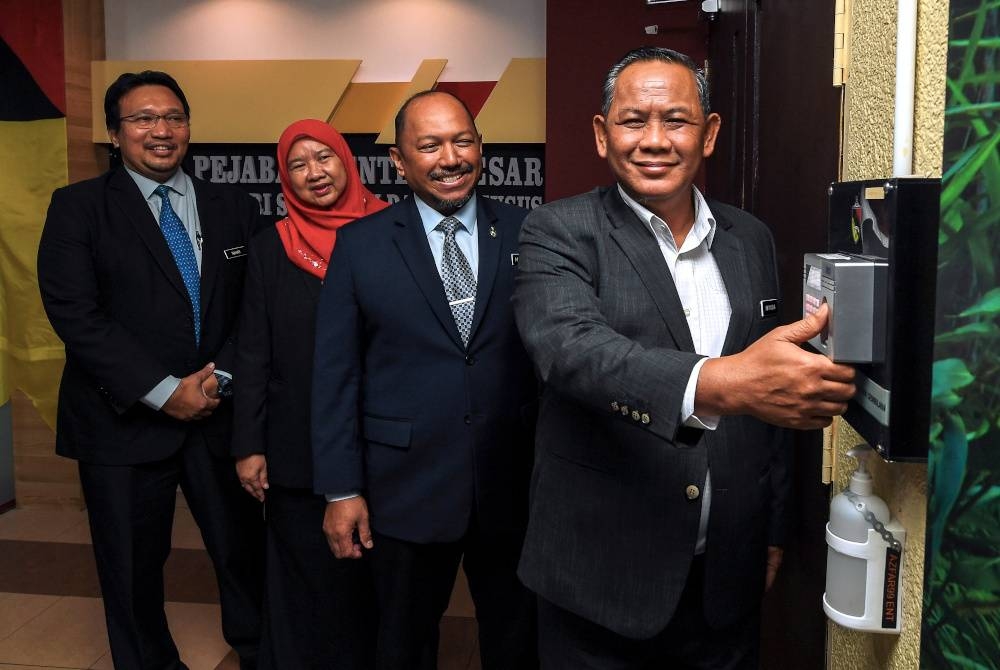 Aminuddin (kanan) mengimbas jari pada perakam waktu sistem pengurusan kehadiran sebagai simbolik memulakan tugas secara rasmi sebagai Menteri Besar Negeri Sembilan di Pejabat Menteri Besar di Wisma Negeri hari ini. - Foto Bernama