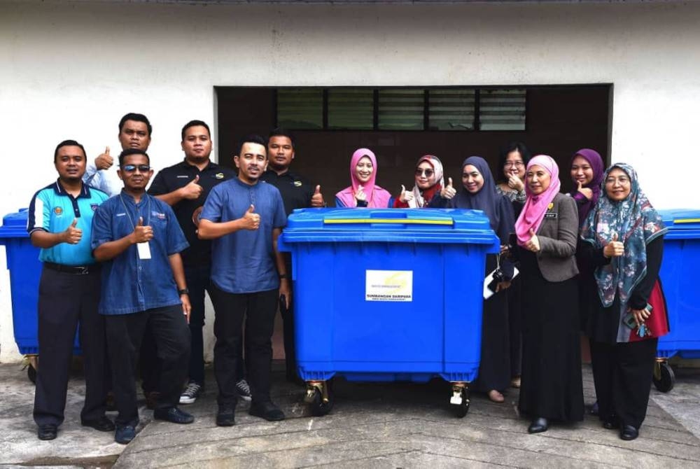 Adzmi (lima dari kiri) menyerahkan sumbangan tong sampah kepada Puteh Melor (tiga dari kanan).