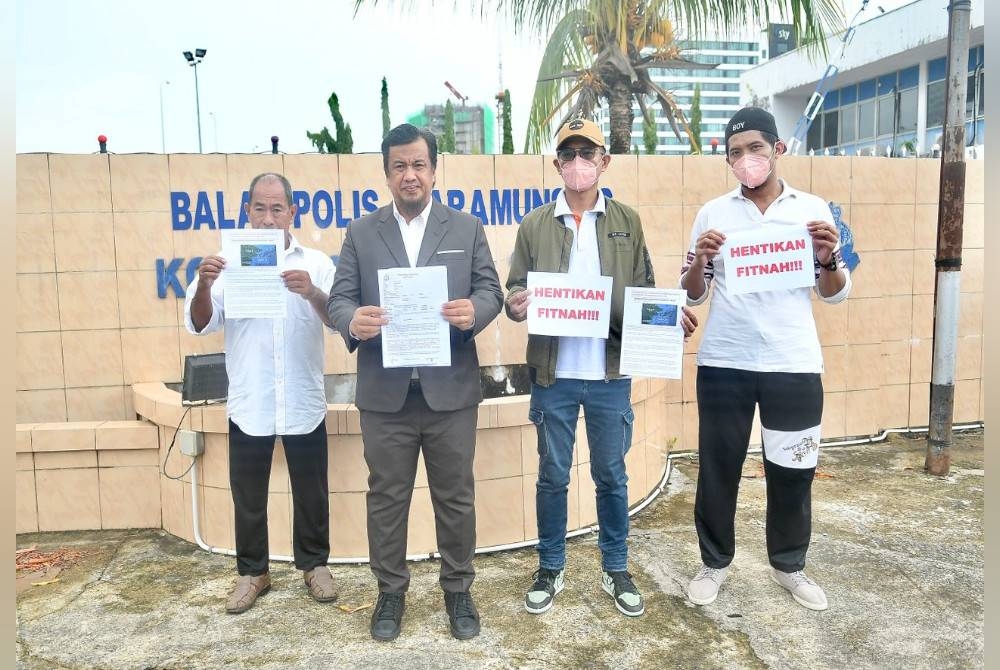 Zulkarnain (dua dari kiri) menunjukkan laporan polis yang dibuat terhadap ADUN Tungku di luar Balai Polis Karamunsing, Kota Kinabalu pada Rabu.