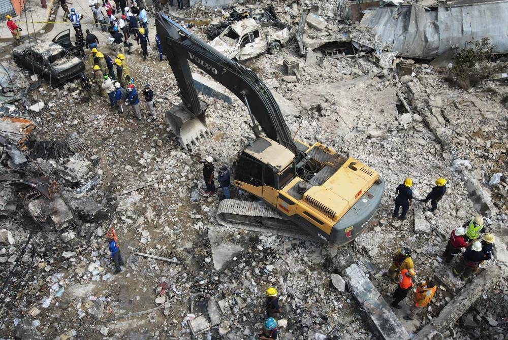 Pandangan dari atas memaparkan para pekerja bertugas di kawasan terjejas akibat letupan di San Cristobal, Dominican. - Foto AFP